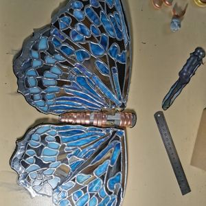 A completed metal sculpture of a copper-coloured butterfly with blue glass wings