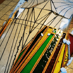 A large, white shape with black lines marking where glass peices should go, with several brightly coloured glass strips added
